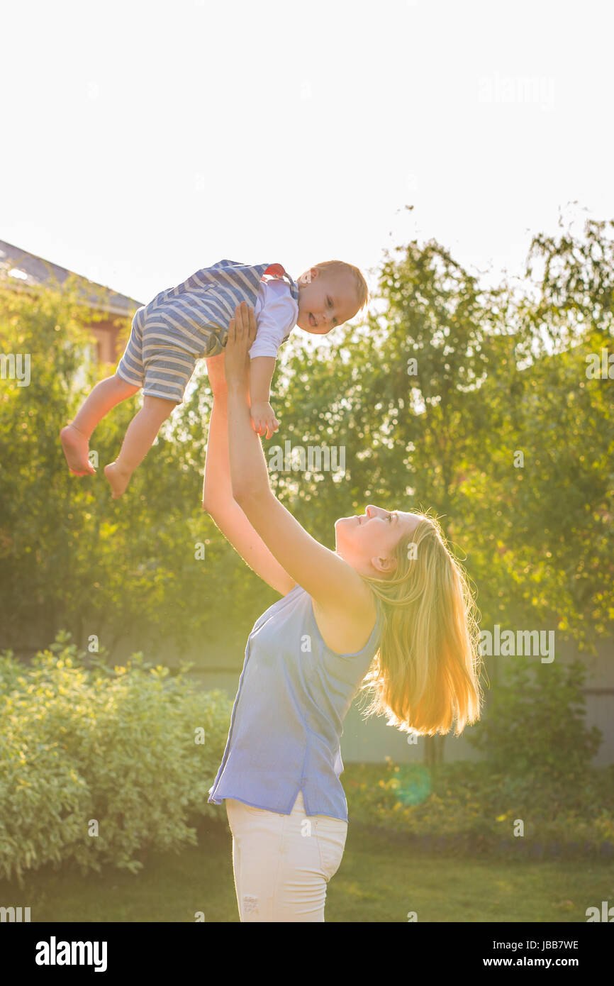 happy harmonious family outdoors. mother throws baby up, laughing and ...