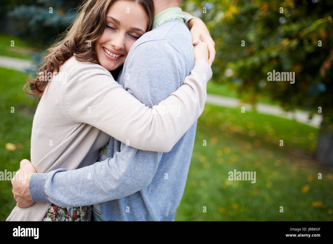 Happy girl embracing her boyfriend in park Stock Photo - Alamy