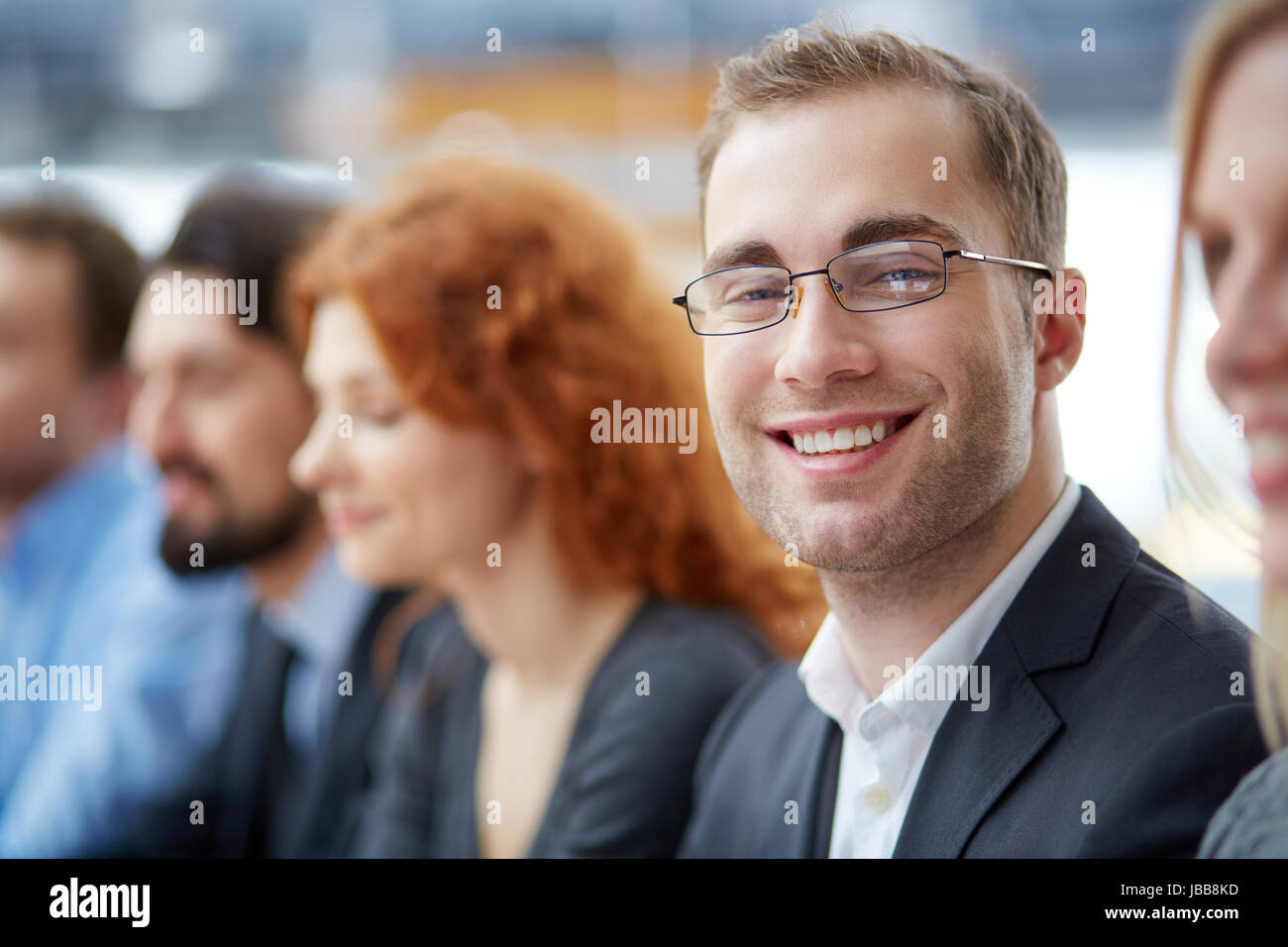 Portrait of young smiling businessman in eyeglasses looking at camera ...