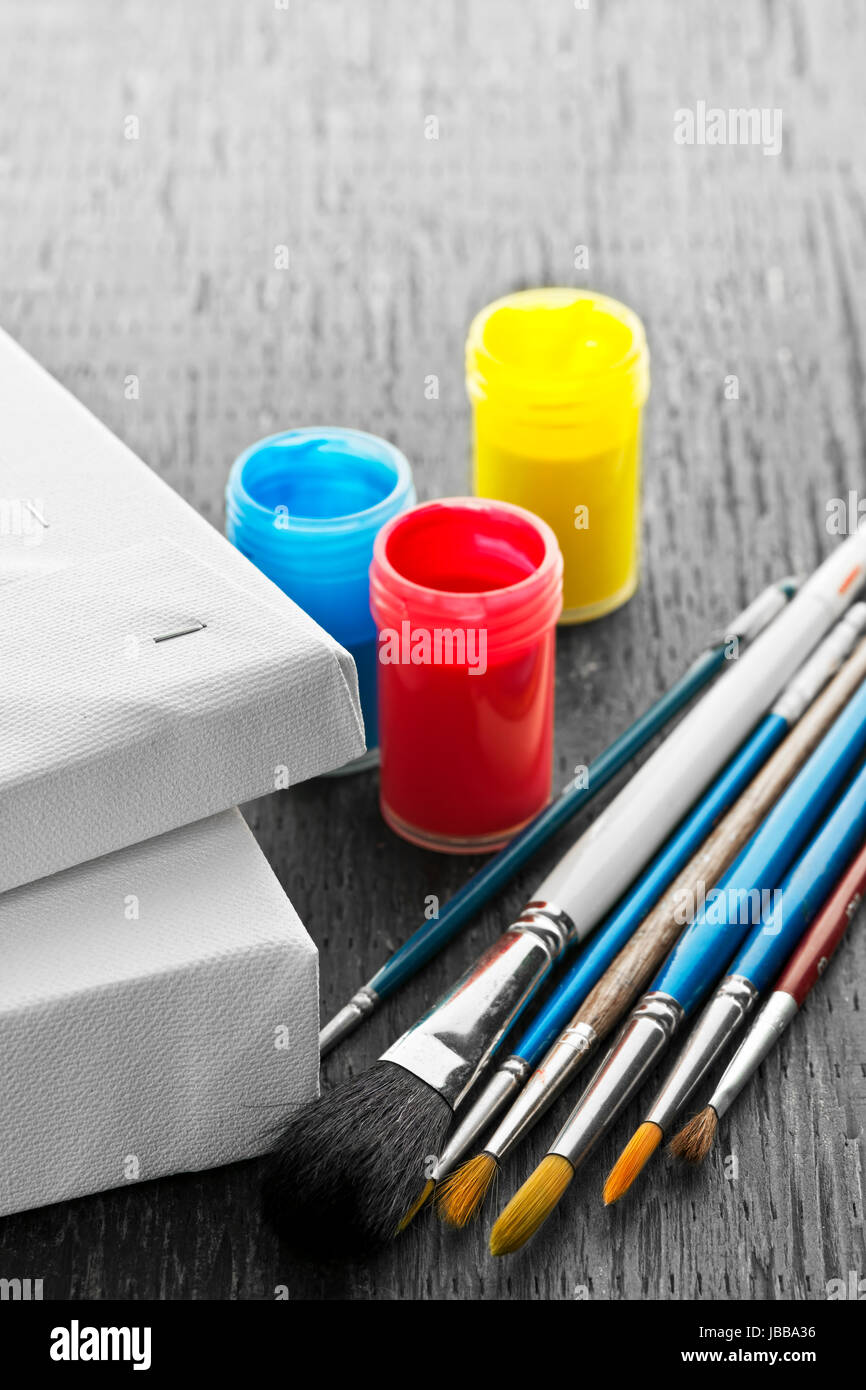 Various sizes of paintbrushes with blank canvas and paints Stock