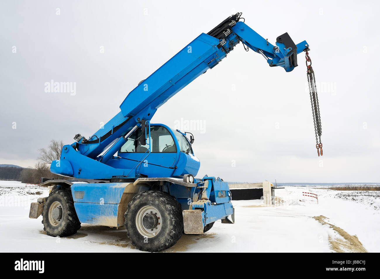 Blauer Kran auf Raedern auf Baustelle im Winter Stock Photo