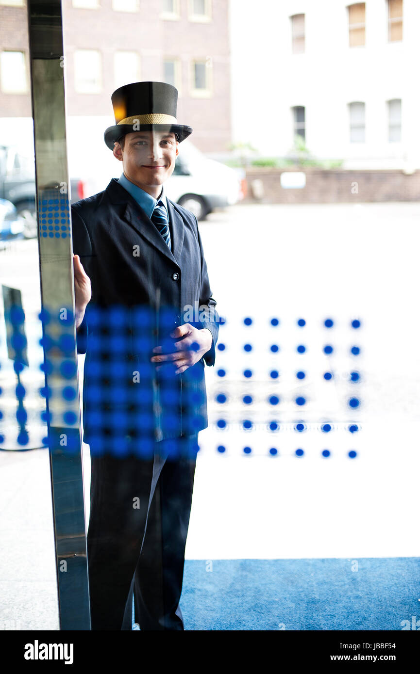 Hotel doorman at your service. Buildings and cars in the background
