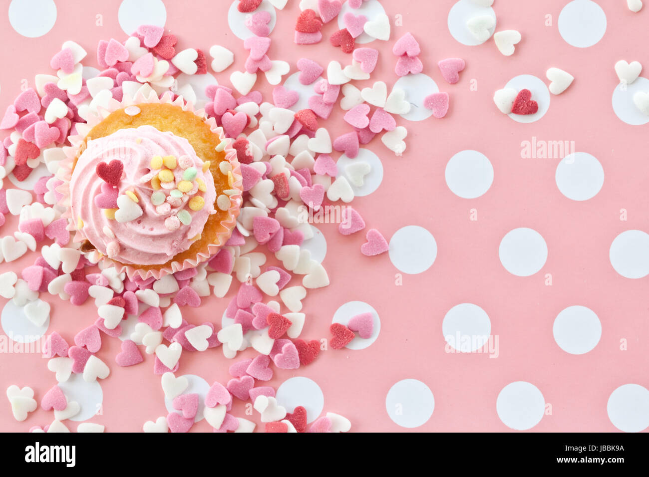 Kleiner bunter cupcake mit rosa Streuseln in Herzform Stock Photo