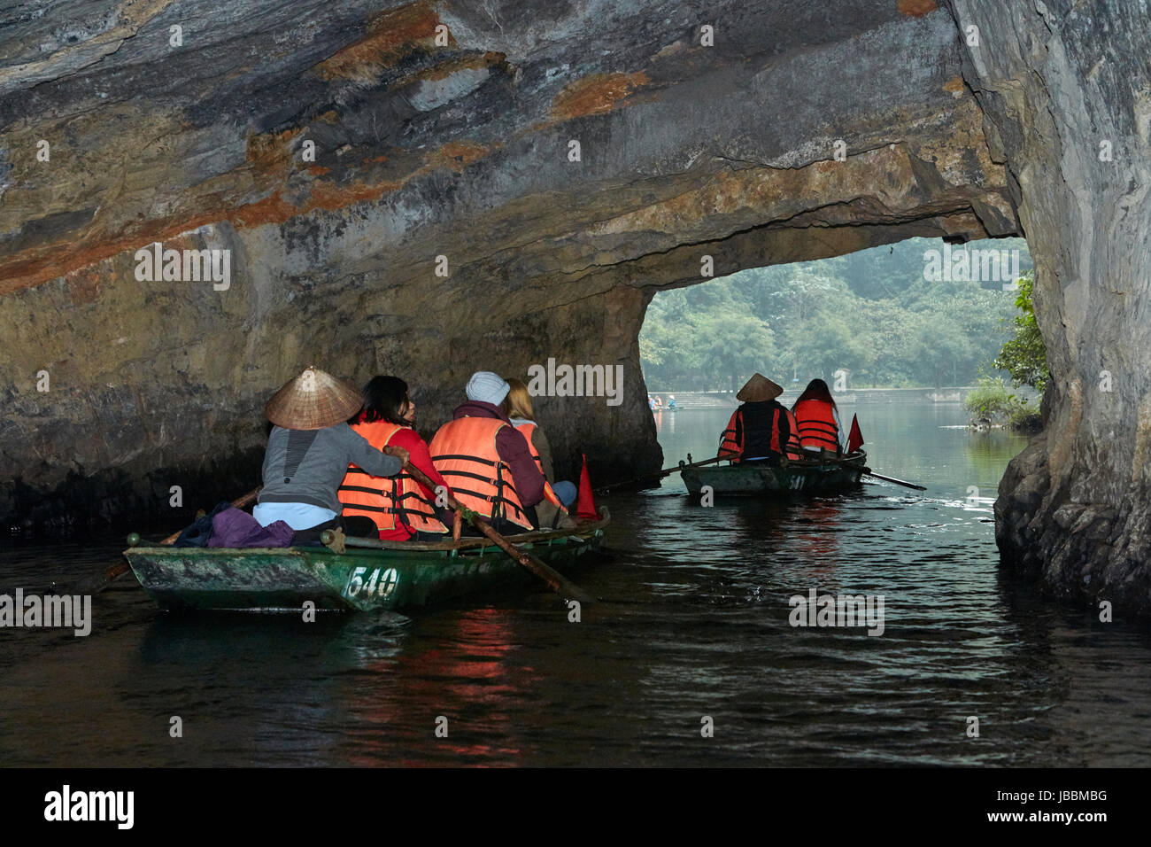Tourists on boat trip through Trang An Grottoes (UNESCO World Heritage Area), near Ninh Binh, Vietnam Stock Photo