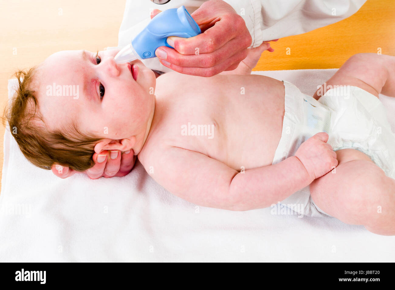 a newborn baby gets noses mucous suctioned with a nose cleaner. Stock Photo