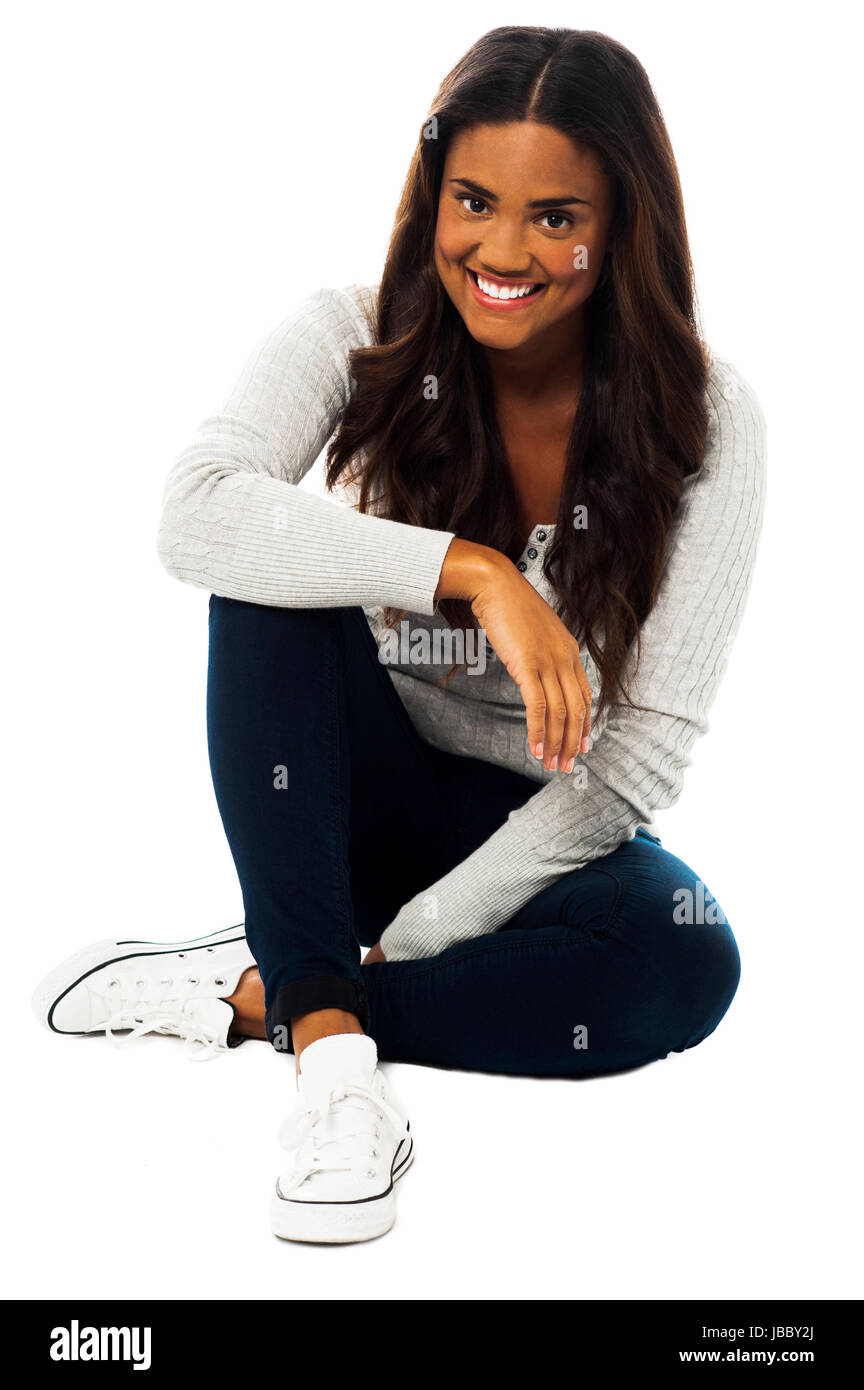 Smiling pretty relaxed girl seated on floor over white Stock Photo - Alamy