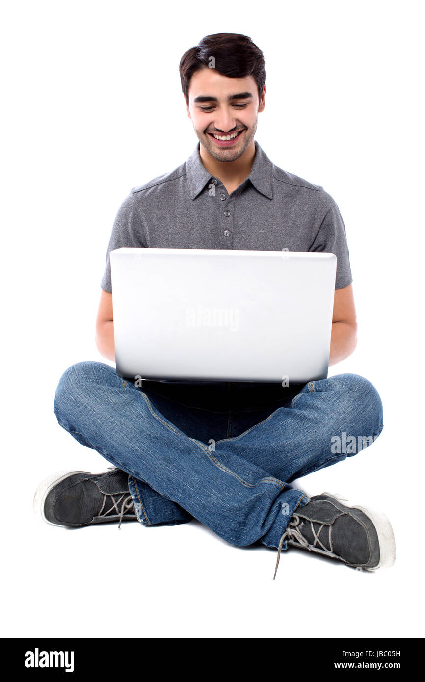 Smiling young guy sitting on the floor with laptop Stock Photo - Alamy
