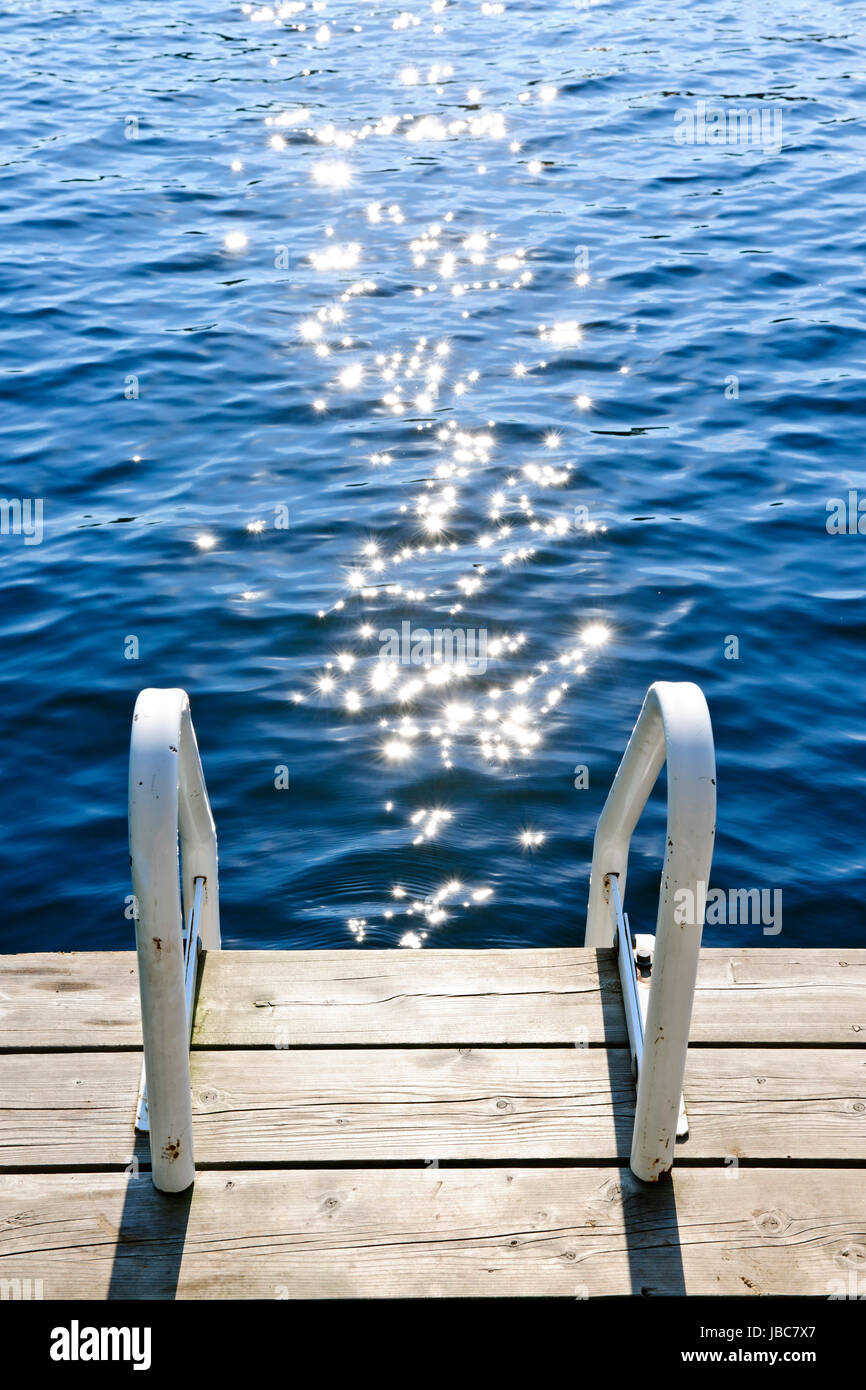 Dock and ladder on calm summer lake with sparkling water in Ontario Canada Stock Photo