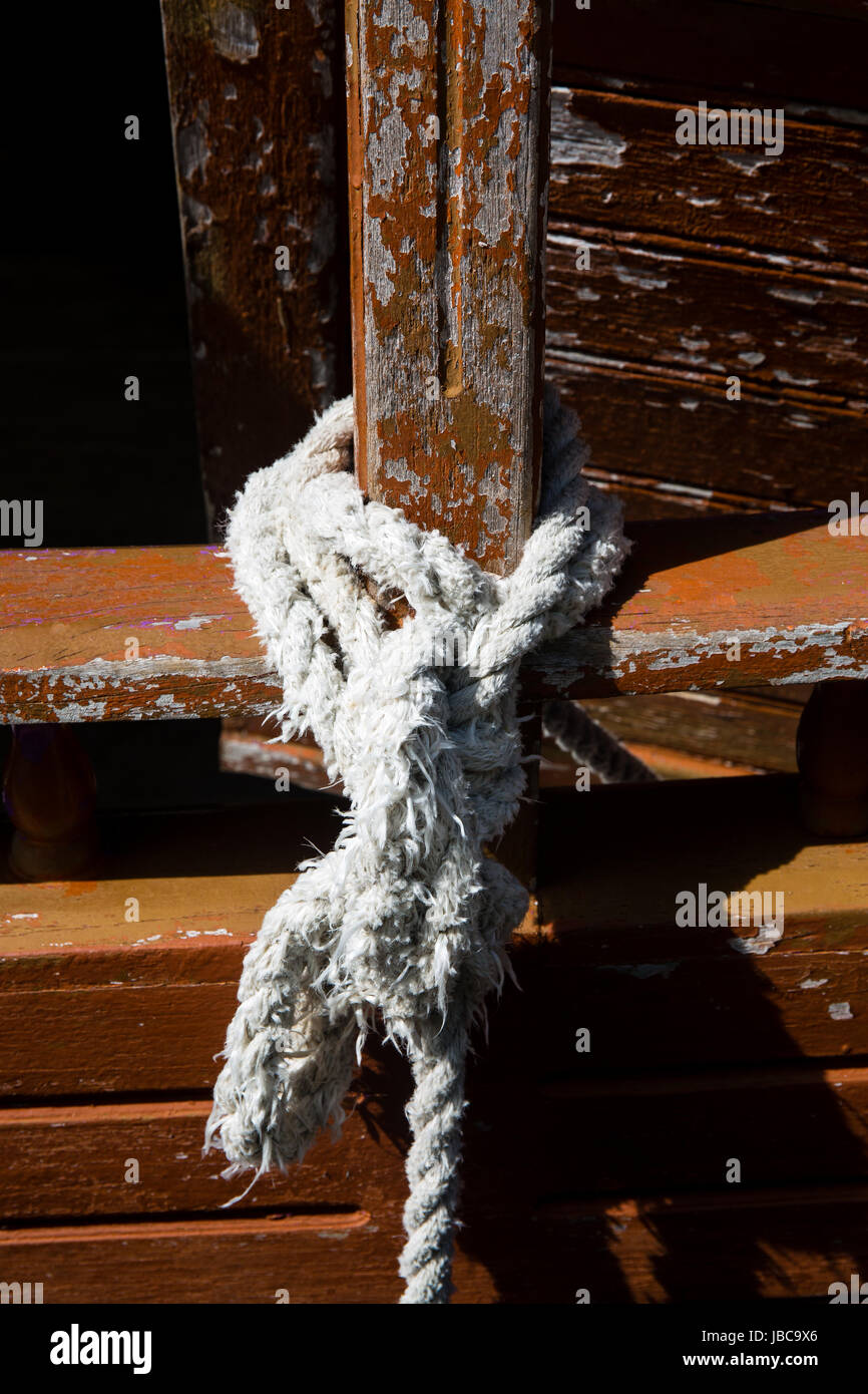 Dhoni boat secured by worn white rope with brown paint flaking off the woodwork Stock Photo