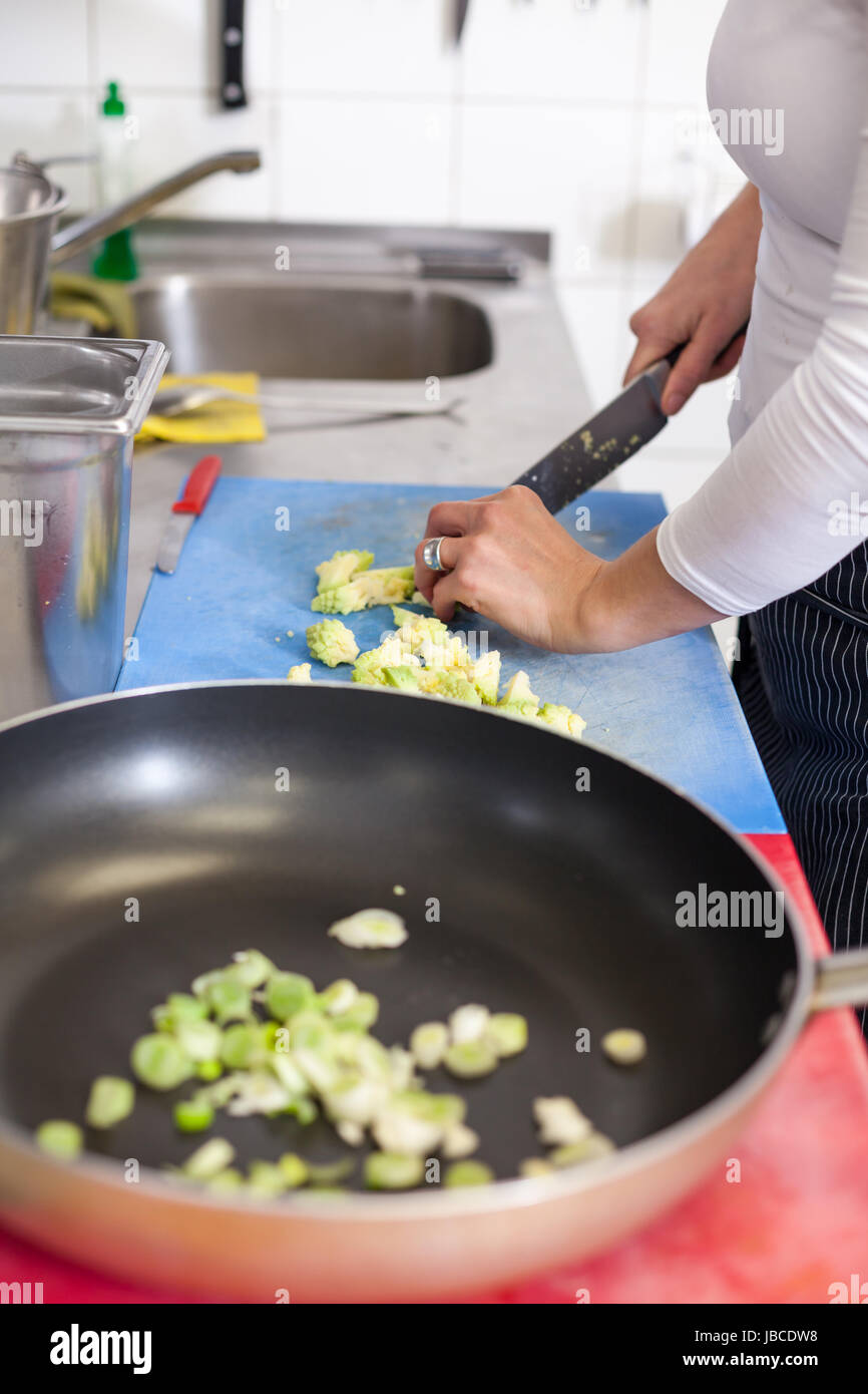 koch schneidet frisches grünes gemüse in der restaurant küche gastronomie essen lebensmittel kochen Stock Photo