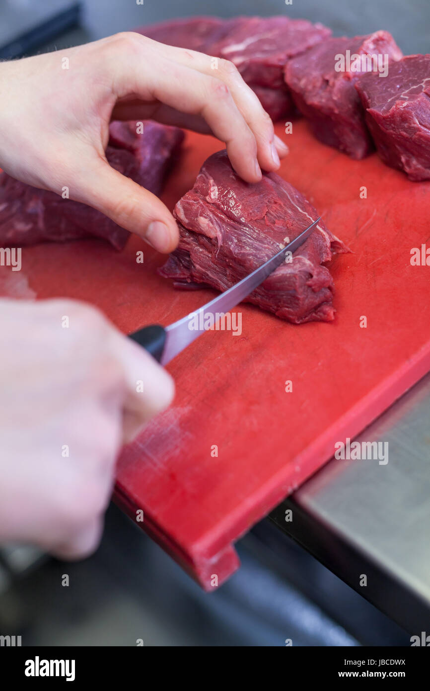 koch schneidet frisches rotes fleisch in der restaurant küche gastronomie lebensmittel arbeit kochen Stock Photo