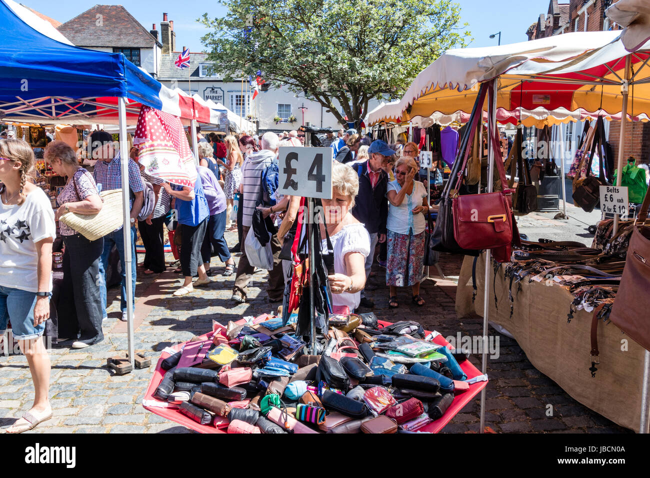 French market set up in English town of Sandwich in Kent. Foreground stall selling bags, handbags and purses. People looking at products. Stock Photo