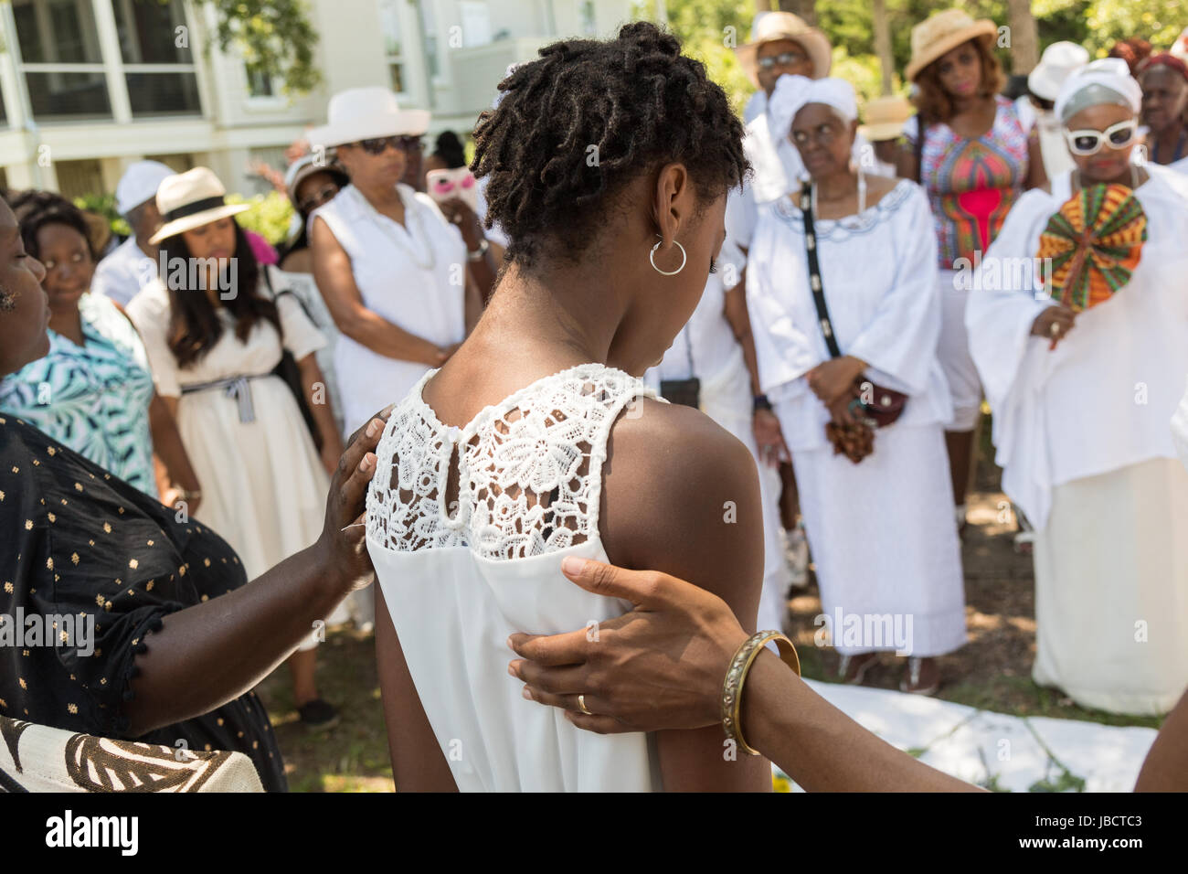 Descendants of enslaved Africans brought to Charleston in the Middle Passage hold a prayer service during a remembrance ceremony at Fort Moutrie National Monument June 10, 2017 in Sullivan's Island, South Carolina. The Middle Passage refers to the triangular trade in which millions of Africans were shipped to the New World as part of the Atlantic slave trade. An estimated 15% of the Africans died at sea and considerably more in the process of capturing and transporting. The total number of African deaths directly attributable to the Middle Passage voyage is estimated at two million Africans. Stock Photo