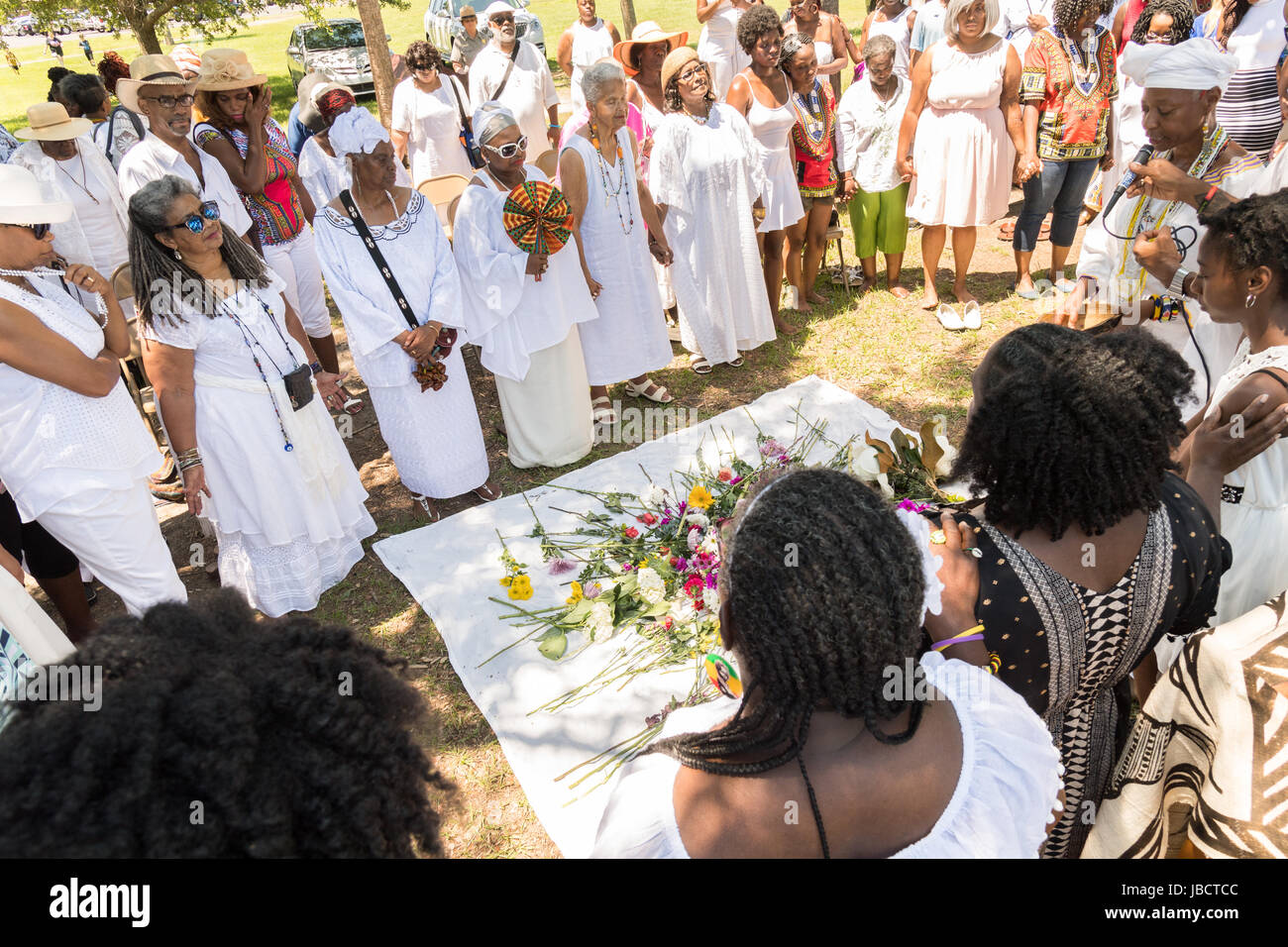 Descendants of enslaved Africans brought to Charleston in the Middle Passage hold a prayer service during a remembrance ceremony at Fort Moutrie National Monument June 10, 2017 in Sullivan's Island, South Carolina. The Middle Passage refers to the triangular trade in which millions of Africans were shipped to the New World as part of the Atlantic slave trade. An estimated 15% of the Africans died at sea and considerably more in the process of capturing and transporting. The total number of African deaths directly attributable to the Middle Passage voyage is estimated at two million Africans. Stock Photo
