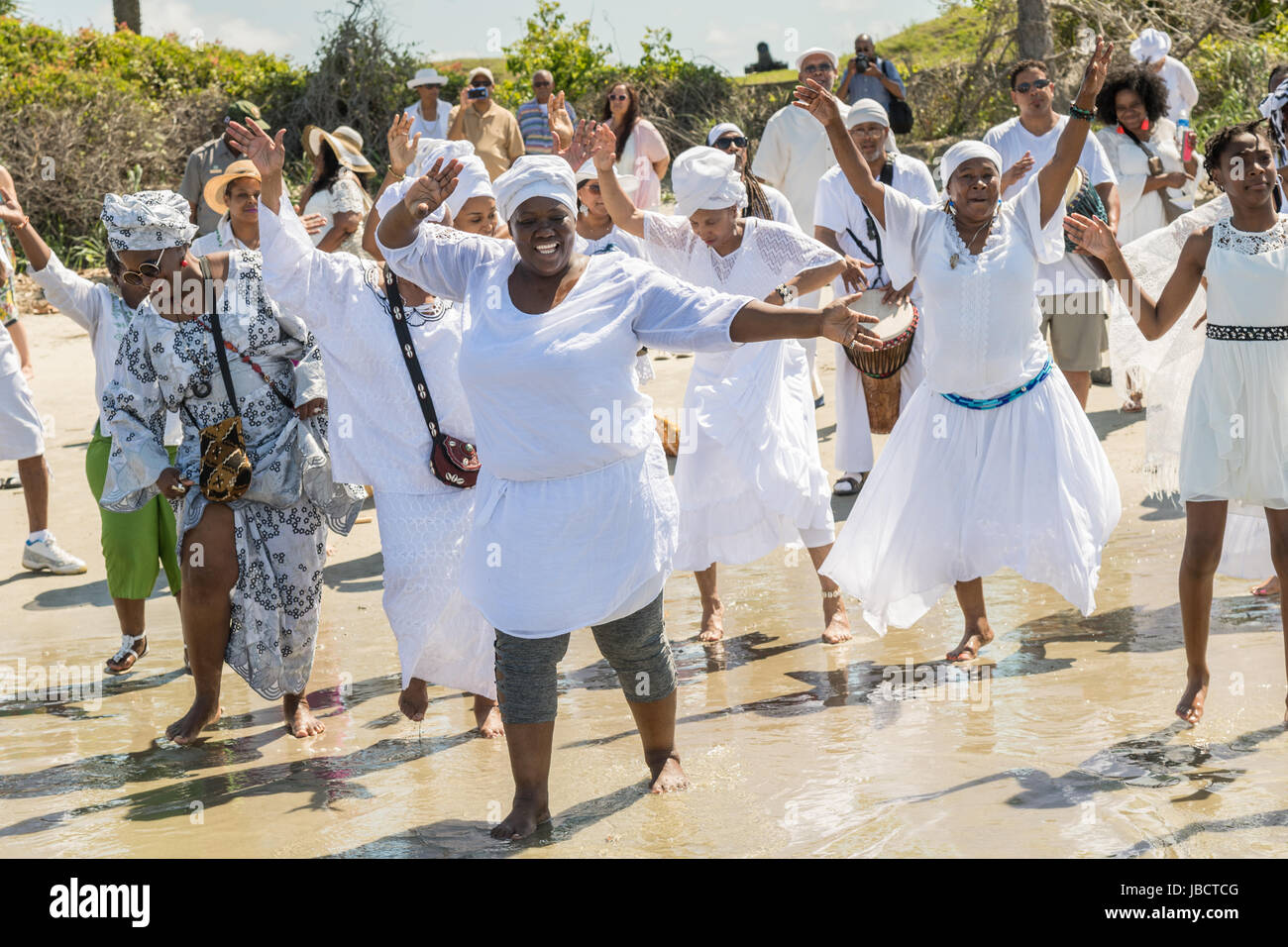 Descendants of enslaved Africans brought to Charleston in the Middle Passage dance to honor their relatives lost during a remembrance ceremony along the ocean front June 10, 2017 in Sullivan's Island, South Carolina. The Middle Passage refers to the triangular trade in which millions of Africans were shipped to the New World as part of the Atlantic slave trade. An estimated 15% of the Africans died at sea and considerably more in the process of capturing and transporting. The total number of African deaths directly attributable to the Middle Passage voyage is estimated at two million Africans. Stock Photo