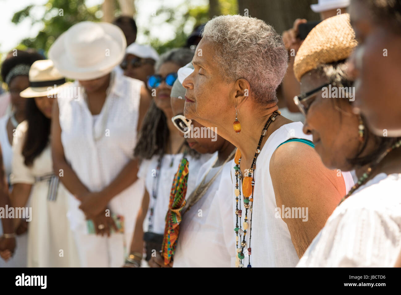Descendants of enslaved Africans brought to Charleston in the Middle Passage hold a prayer service during a remembrance ceremony at Fort Moutrie National Monument June 10, 2017 in Sullivan's Island, South Carolina. The Middle Passage refers to the triangular trade in which millions of Africans were shipped to the New World as part of the Atlantic slave trade. An estimated 15% of the Africans died at sea and considerably more in the process of capturing and transporting. The total number of African deaths directly attributable to the Middle Passage voyage is estimated up to two million Africans Stock Photo