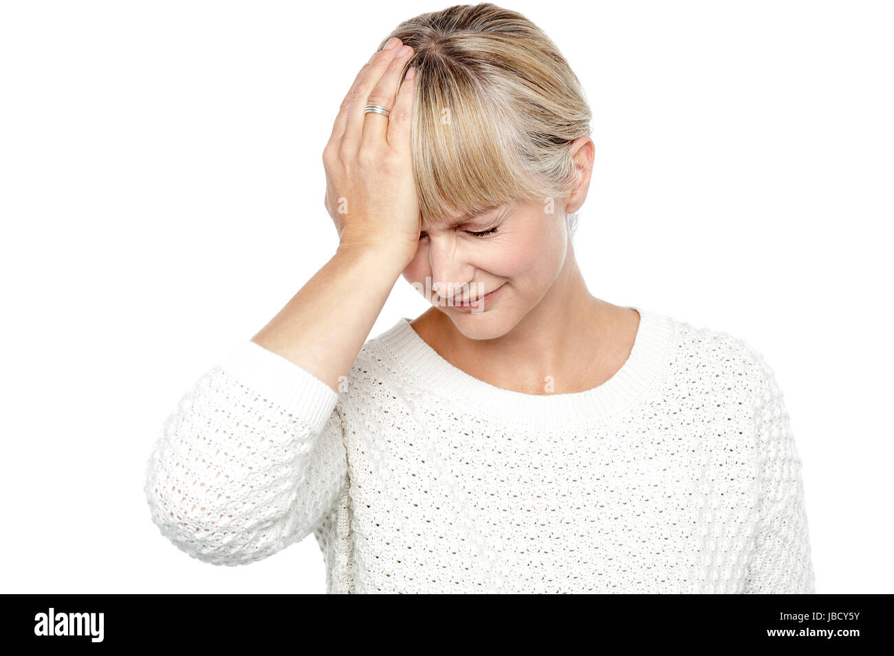 Sad middle aged woman suffering from headache. Placing her hand on forehead. Stock Photo