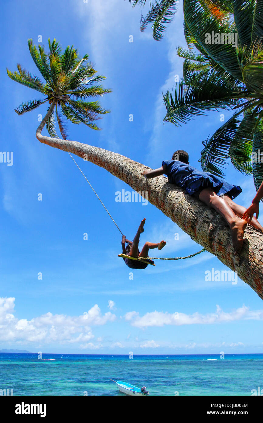 Local kids swinging on a rope swing in Lavena village, Taveuni Island