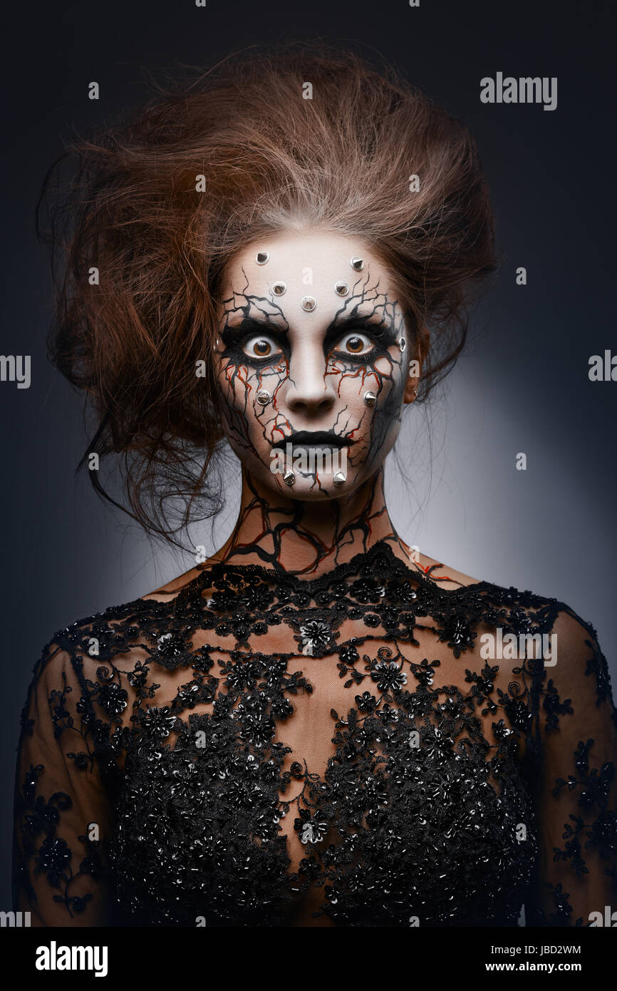 A girl standing like a statue in a creepy halloween costume of a witch