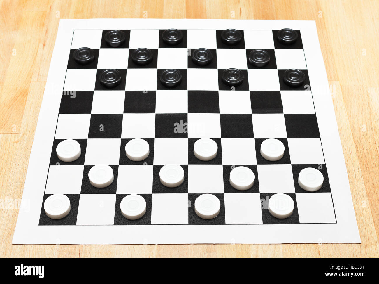 Starting position on vinyl 8x8 checkers board on wooden table Stock