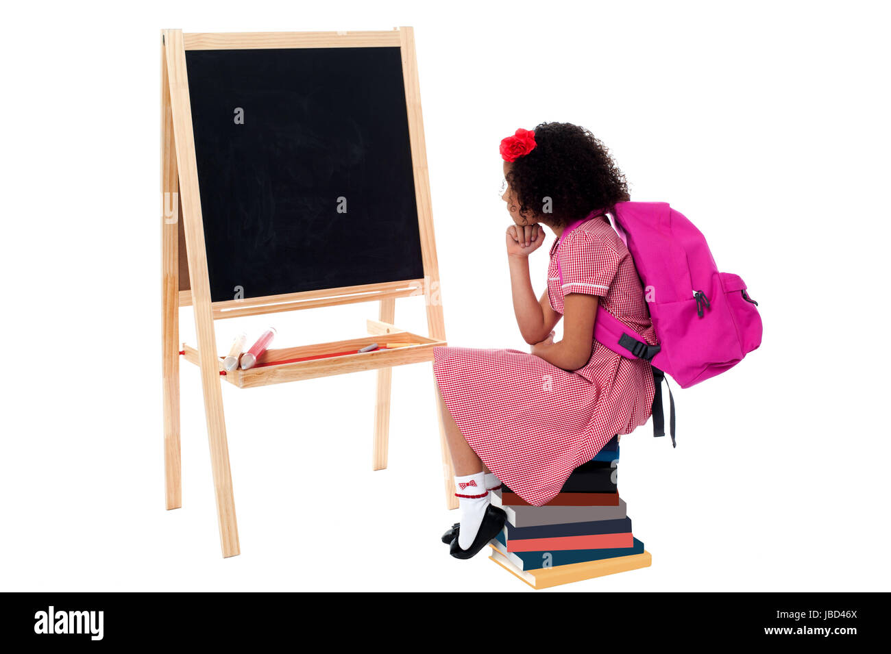 School girl sitting on stack of books and wondering Stock Photo - Alamy