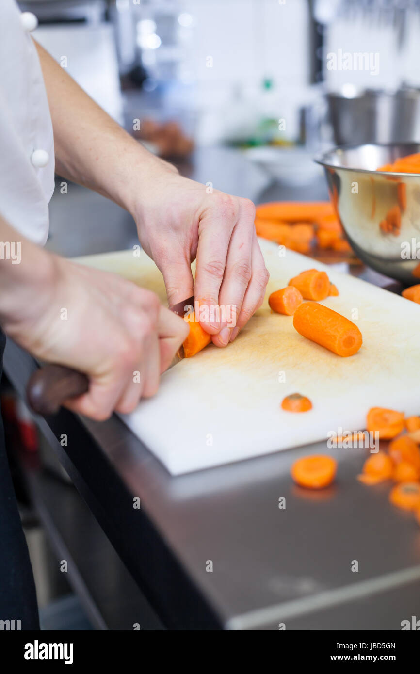 koch schneidet frische karotten in der restaurant küche vorberetung zutaten essen nahrung gastronomie arbeit Stock Photo