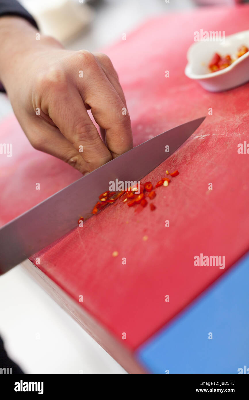koch schneidet frische rote chilli klein in der restaurant küche gatsronomie lebensmittel essen Stock Photo