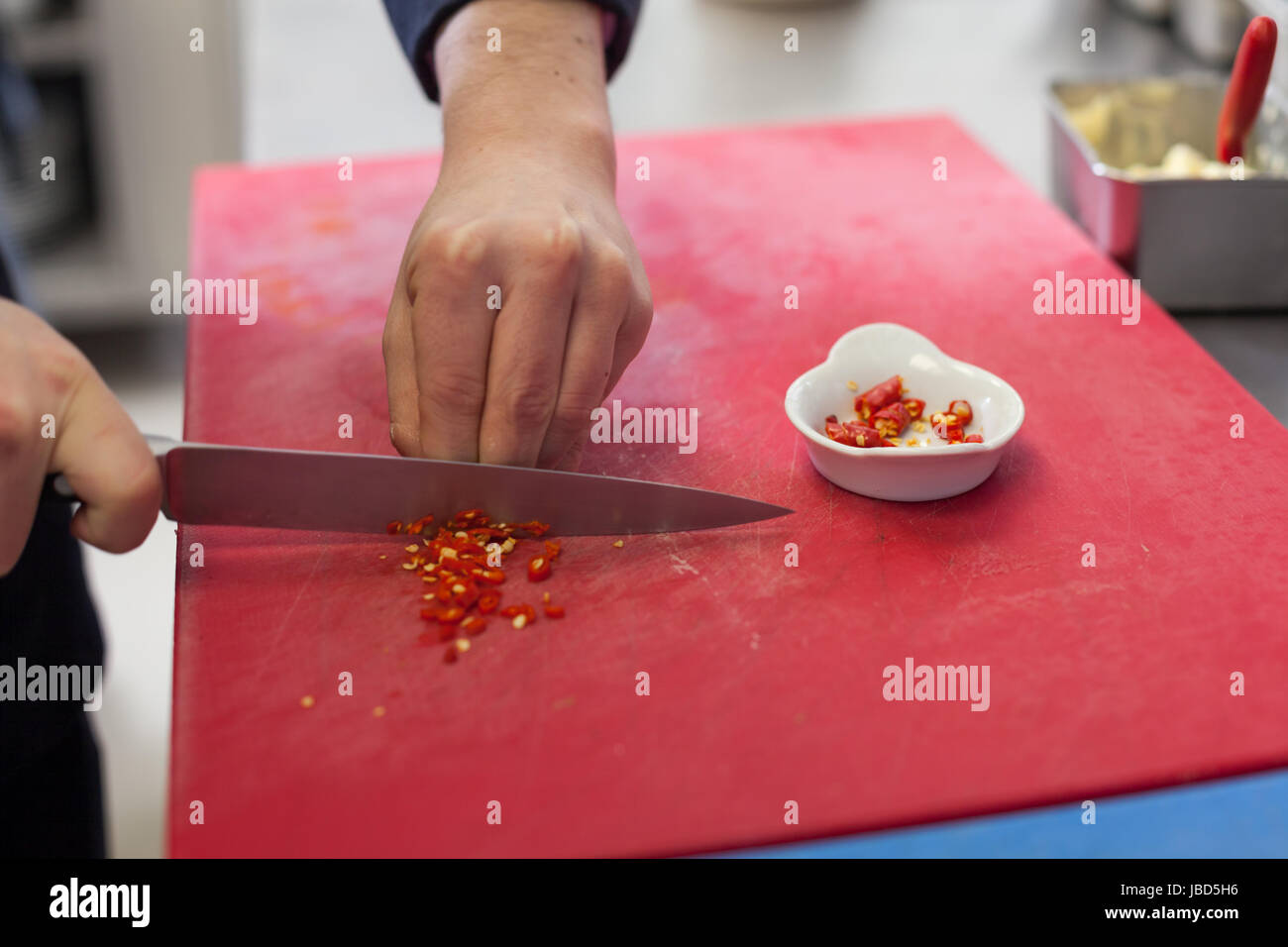 koch schneidet frische rote chilli klein in der restaurant küche gatsronomie lebensmittel essen Stock Photo