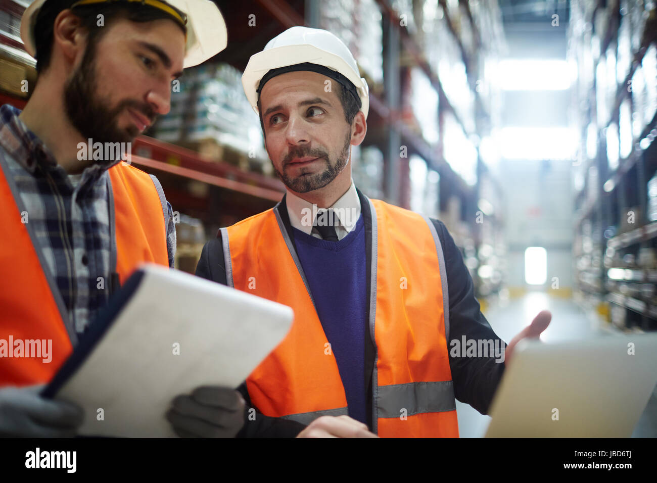 Supervisor explaining data to one of storehouse workers Stock Photo - Alamy