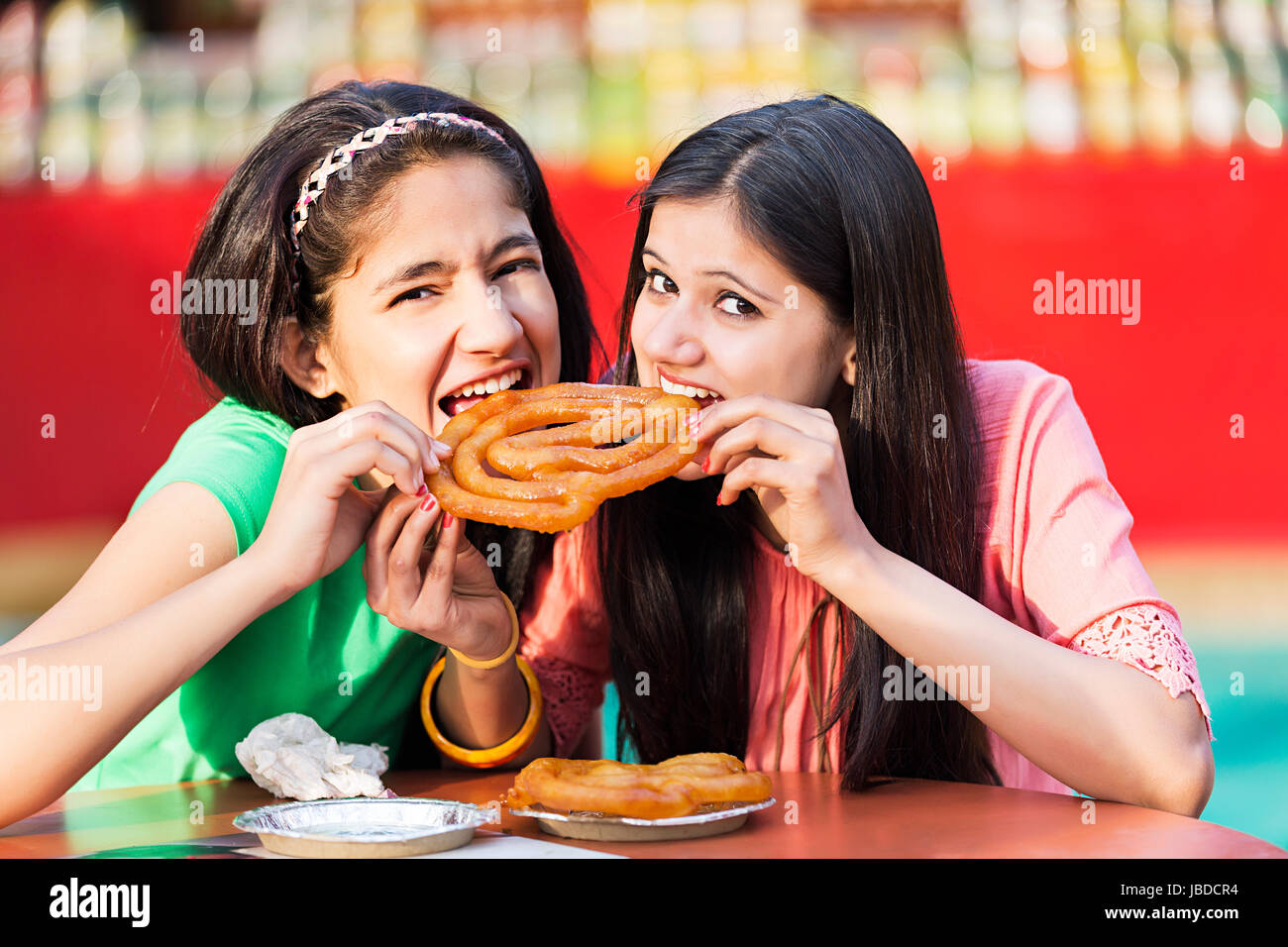 2 Young Girls Friend Eating Jalebi Biting Together Enjoy Restaurant Stock Photo