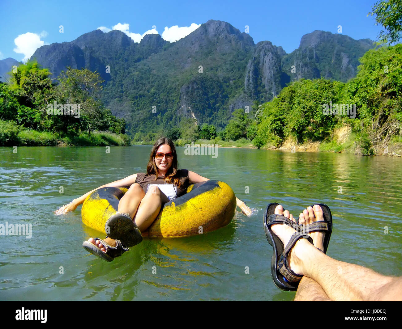 Couple going down Nam Song River in a tube surrounded by karst scenery in Vang Vieng, Laos. Tubing is a popular tourist activity in Vang Vieng. Stock Photo