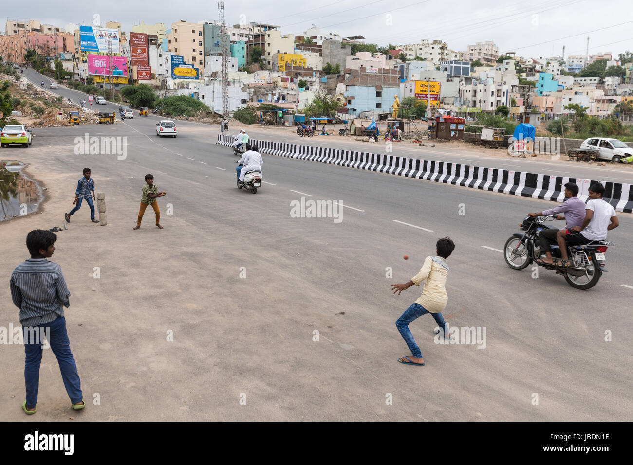 Indian kids playing cricket on a busy street in Hyderabad,India Stock Photo