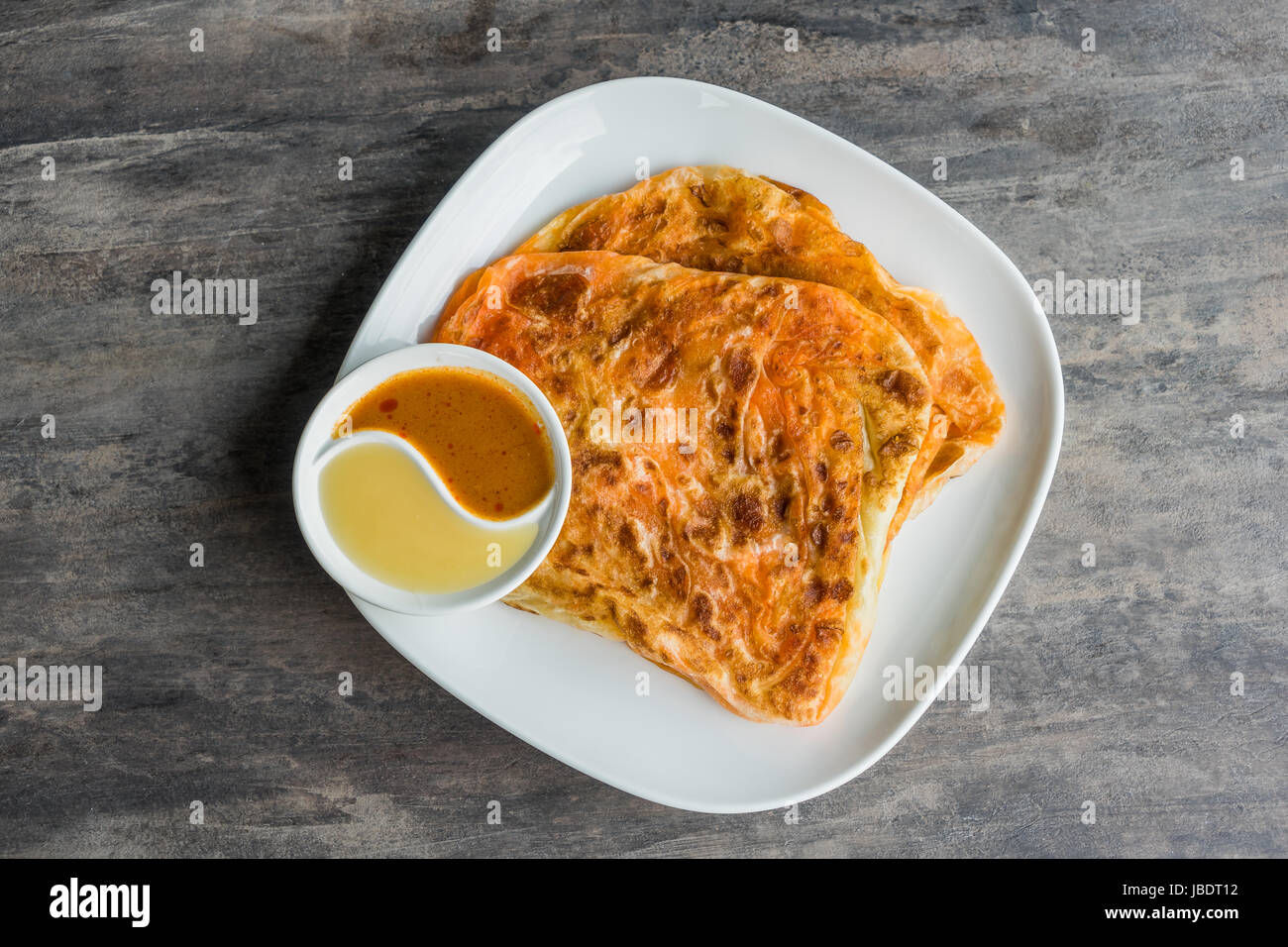 Indian Roti Prata with Condensed milk and Curry Sauce, close up of rustic Indian Roti fried pancake Stock Photo