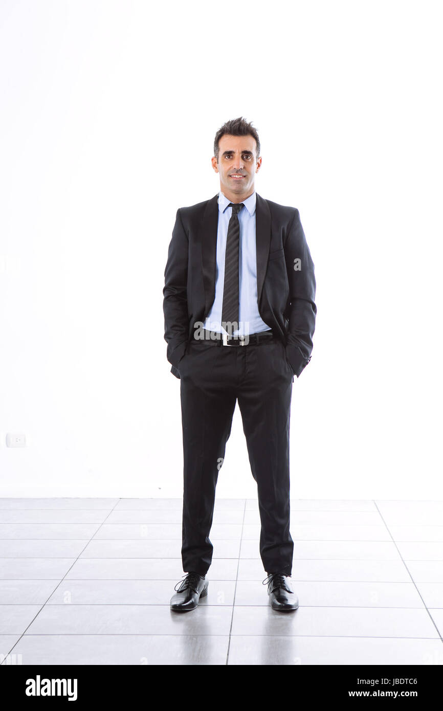 A 35 - 40 years with suit office man smiling cool modern look hands in the pockets studio shot over a white background full shot Stock Photo