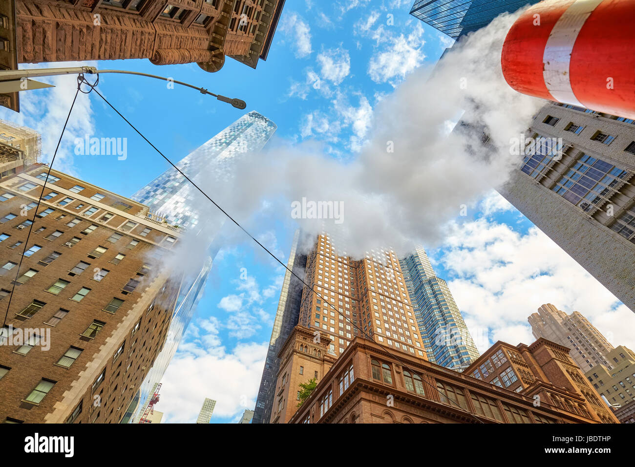 Looking up at Manhattan skyscrapers with steam coming from street pipe, New York City, USA. Stock Photo