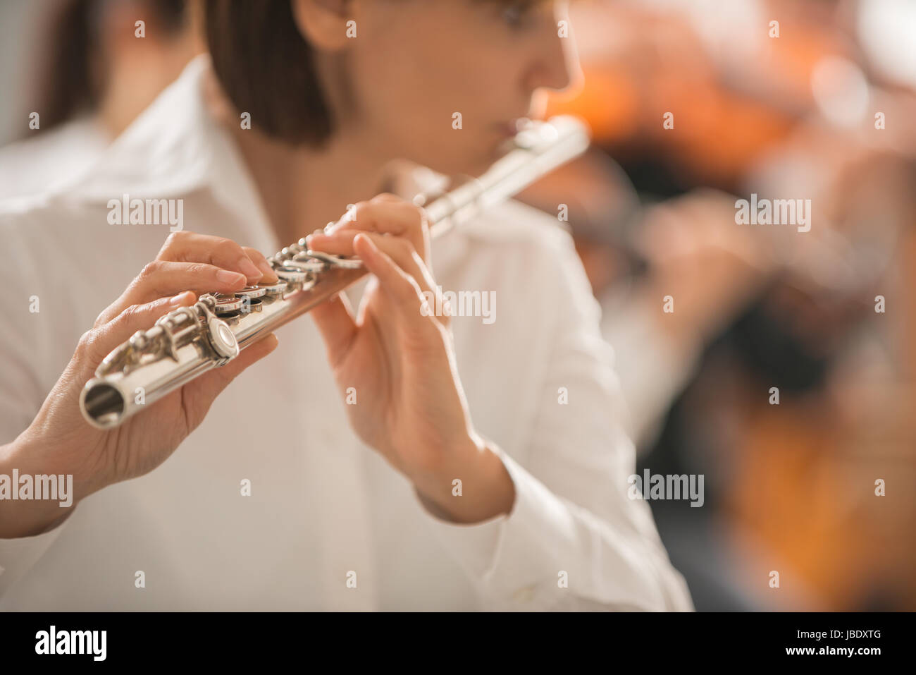 Professional female flute player performing with classical music symphony orchestra, unrecognizable person Stock Photo