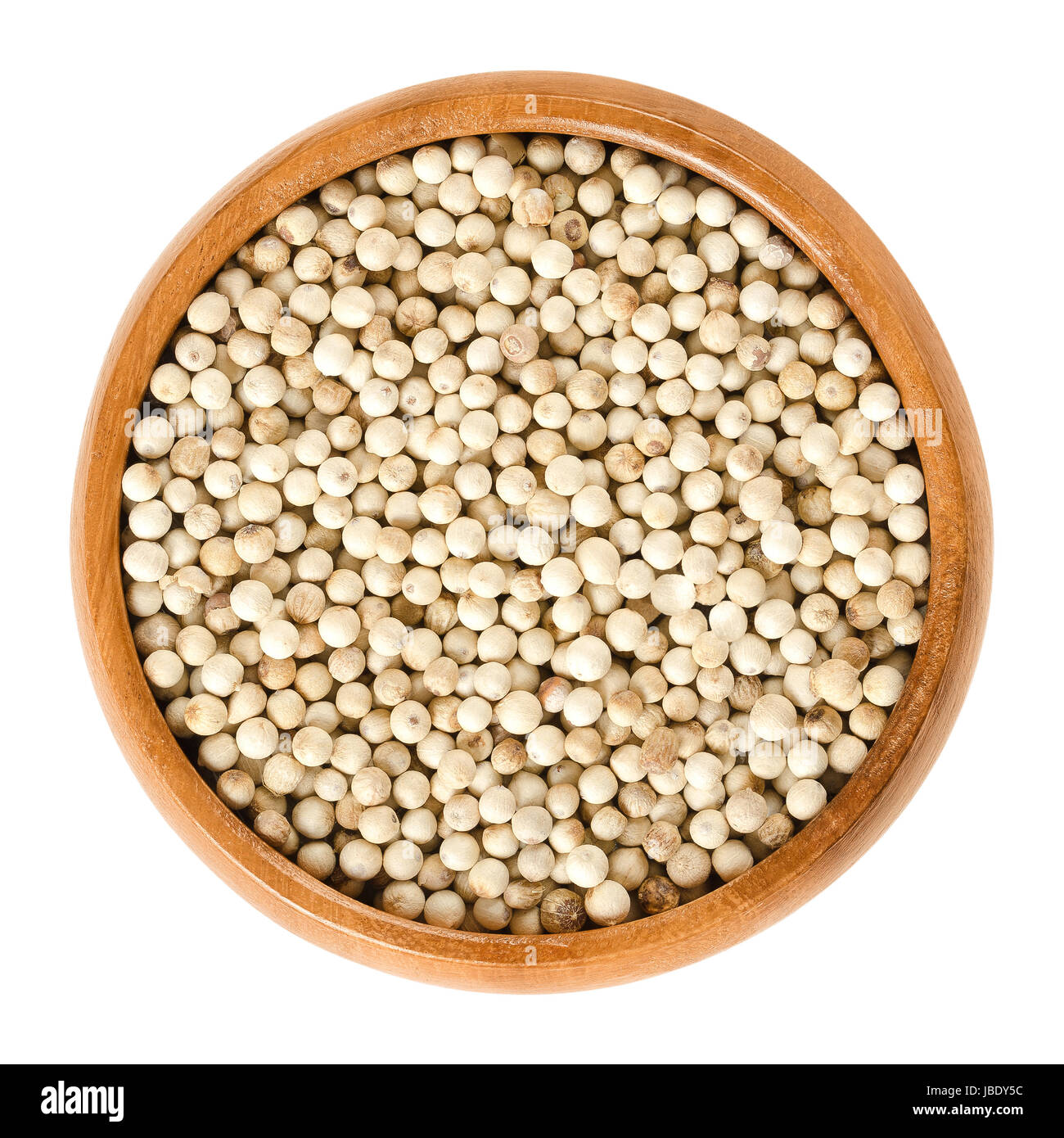 White pepper in wooden bowl. Dried berries of Piper nigrum, called peppercorns. Seed of pepper plant without darker-coloured skin. Spice. Stock Photo
