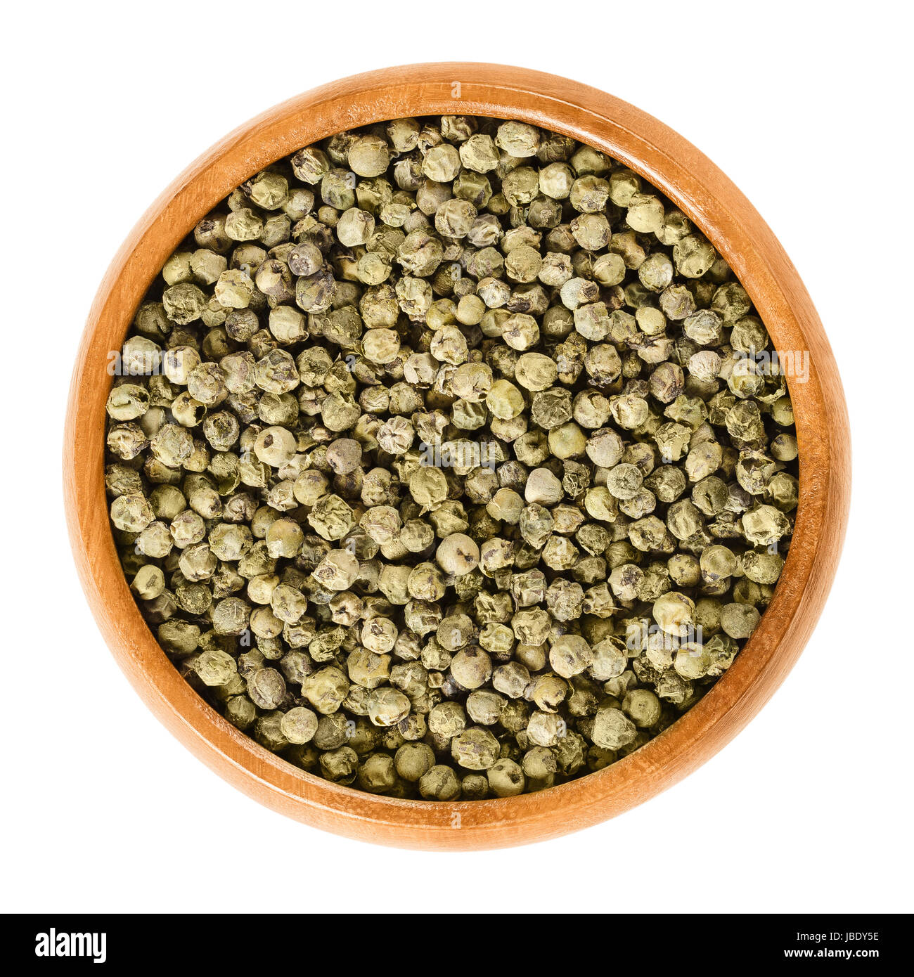 Green pepper in wooden bowl. Dried berries of Piper nigrum are called