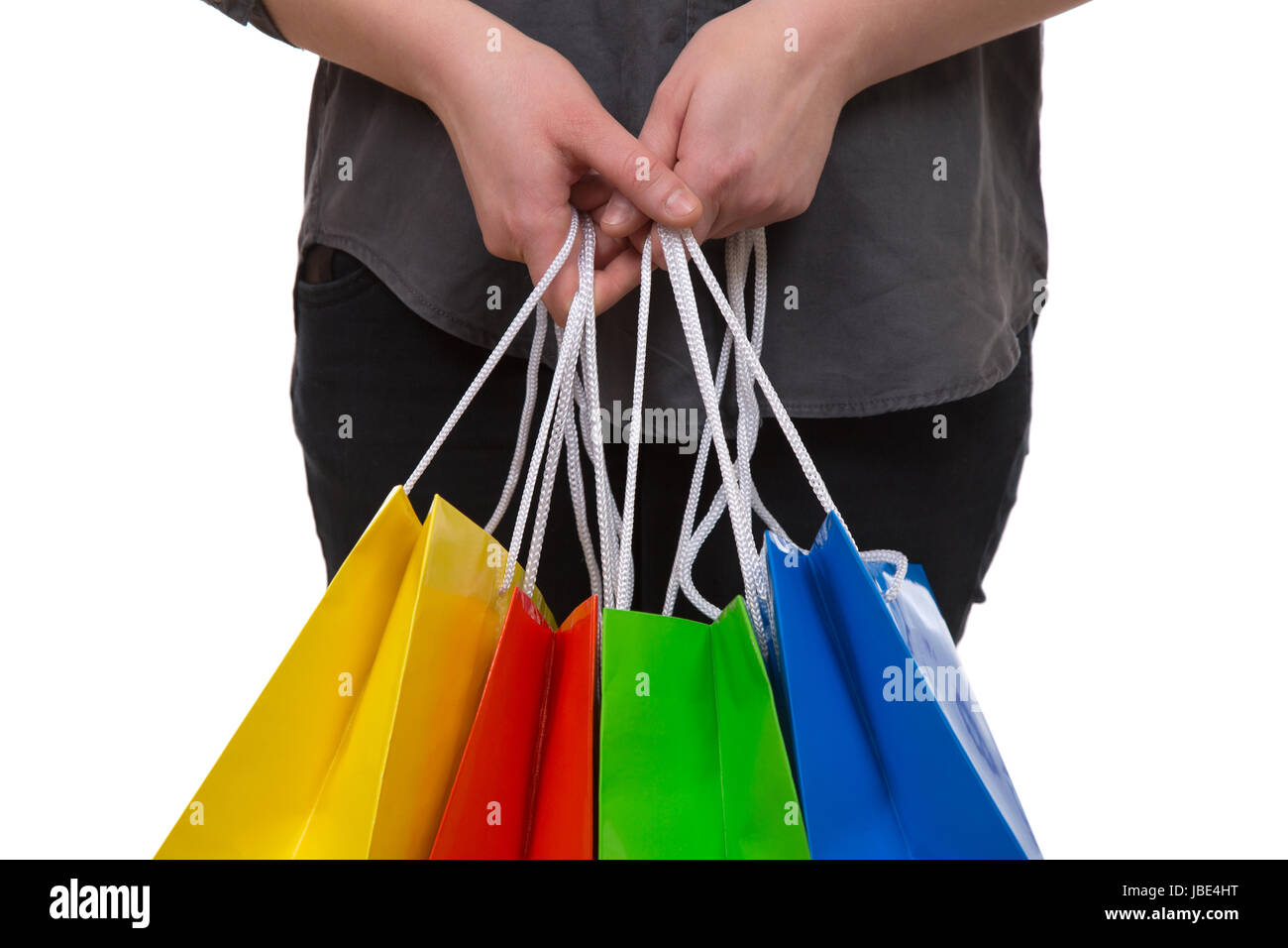 Eine Frau hält bunte Einkaufstaschen fürs Shopping in der Hand, isoliert vor einem weissen Hintergrund Stock Photo