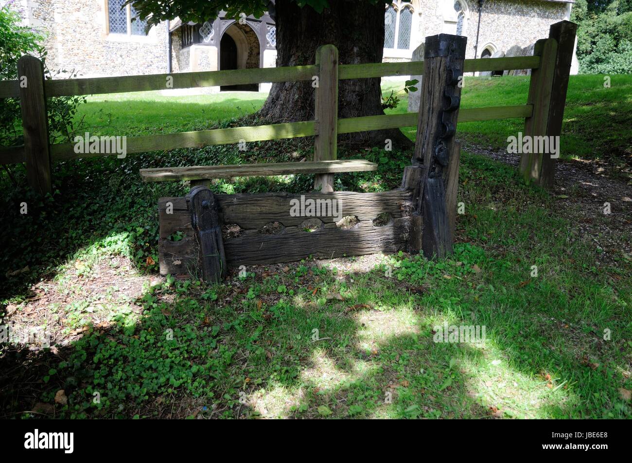 The Stocks and Whipping Post, Brent Pelham, Hertfordshire, are just outside the churchyard shaded by trees Stock Photo