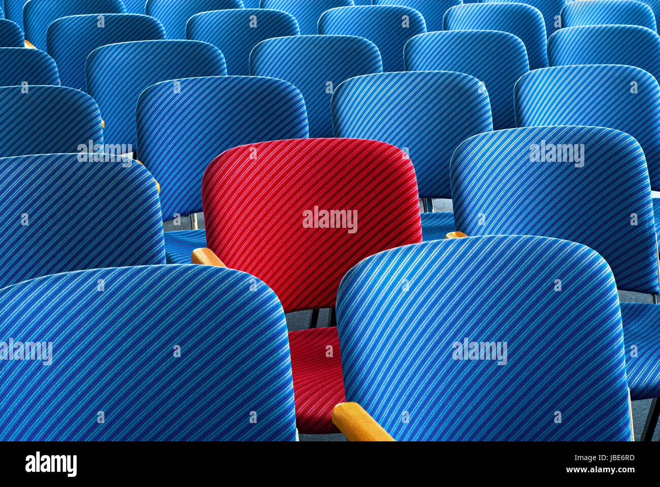 Roter Sitz inmitten von leeren blauen Sitzplätzen als Blickfang Stock Photo
