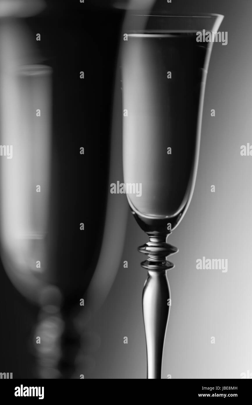 Detail view of the Topparts Zwieer champagne glasses in front of background with brightness gradient; Monochrome. The focus is on the rear glass. Stock Photo