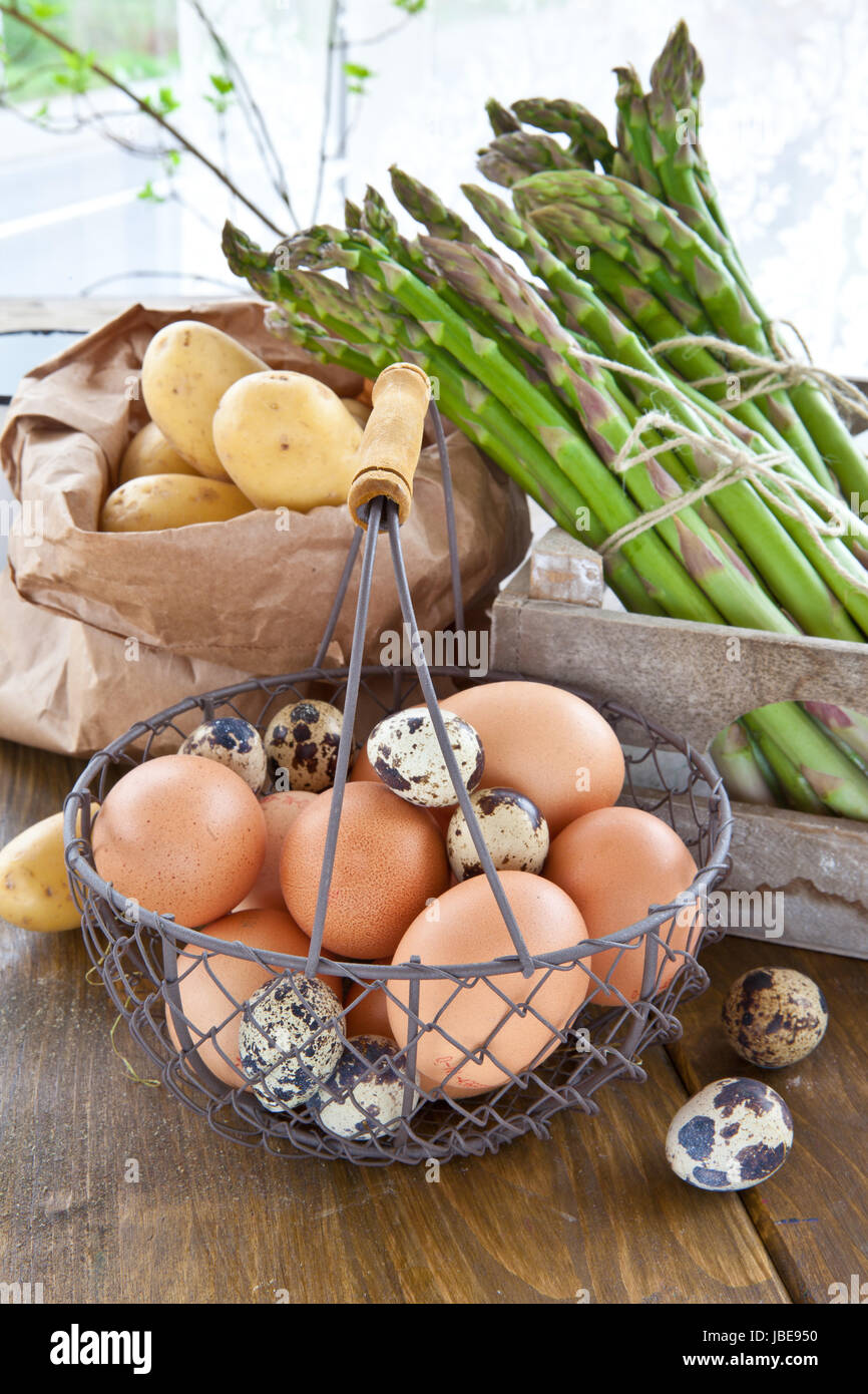 Frischer gruener Spargel , Bio-Kartoffeln und verschiedene rohe Eier Stock Photo