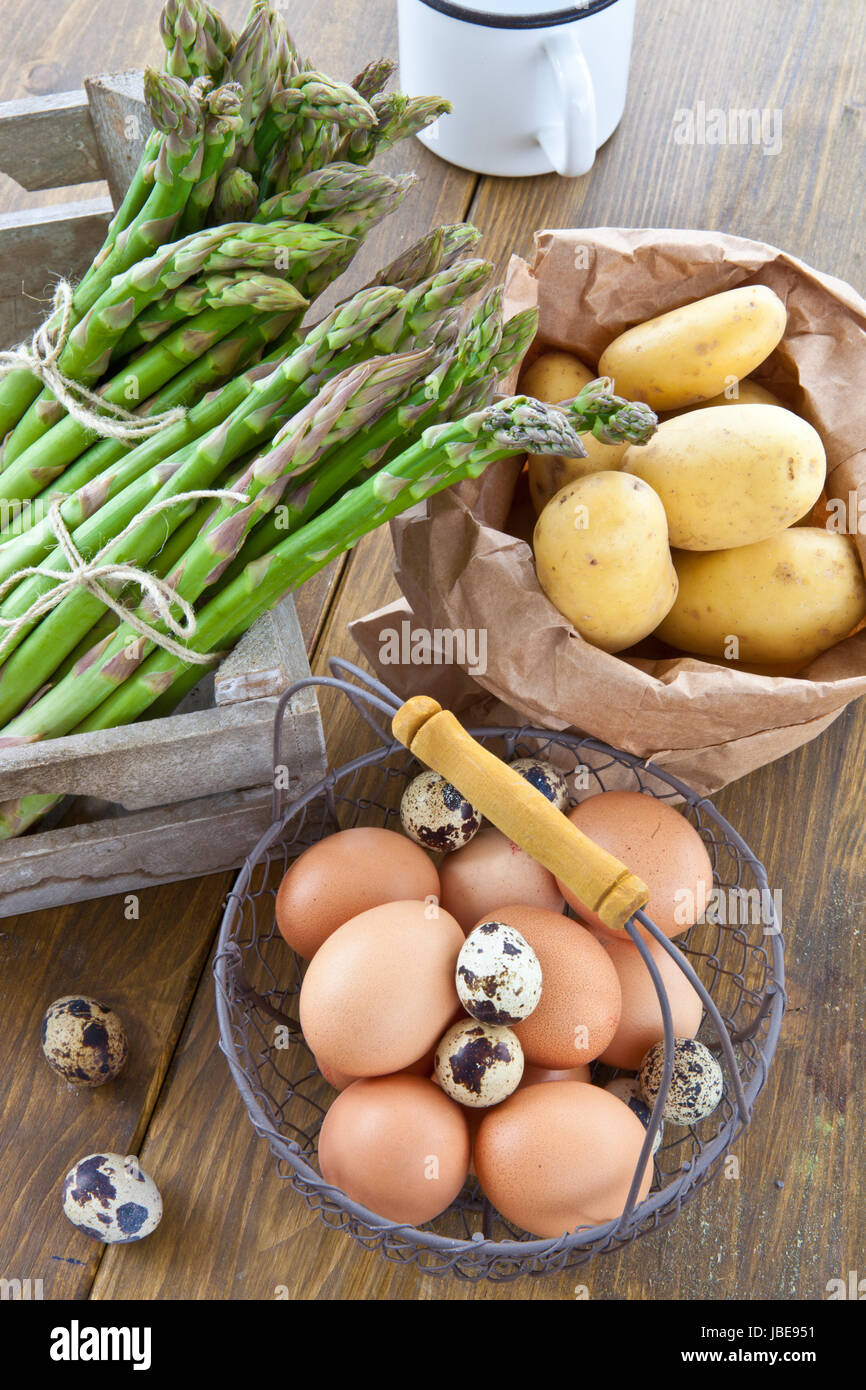 Frischer gruener Spargel , Bio-Kartoffeln und verschiedene rohe Eier Stock Photo