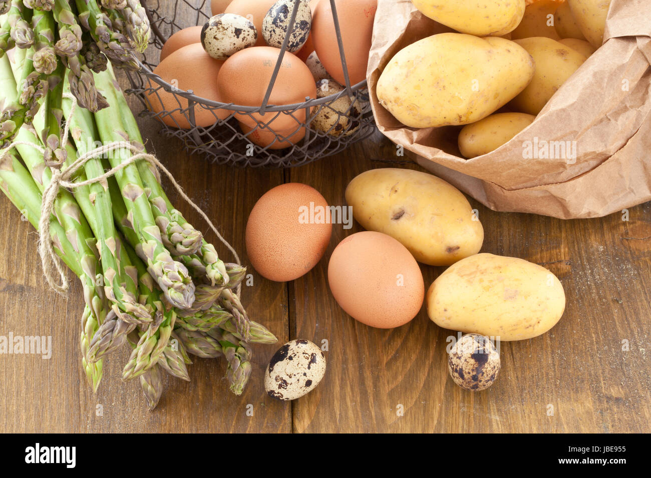 Frischer gruener Spargel , Bio-Kartoffeln und verschiedene rohe Eier in Holzkiste Stock Photo