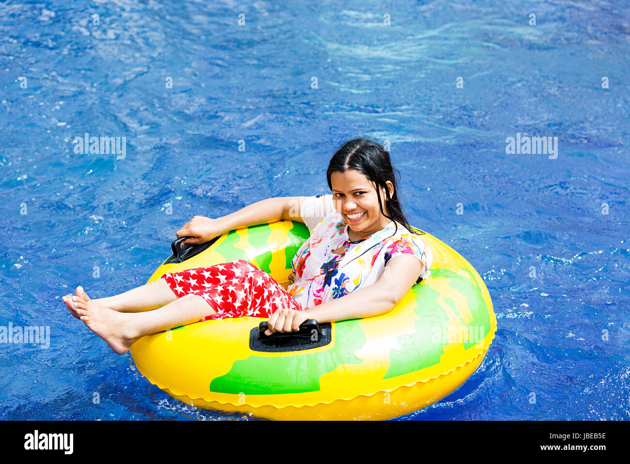 Happy 1 Indian Young Woman relaxing inflatable ring resort pool Enjoying Smiling Stock Photo