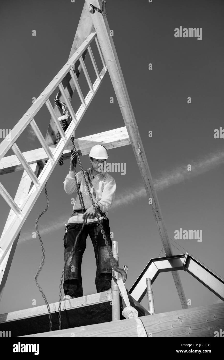 Real construction worker at work with winch on roof construction