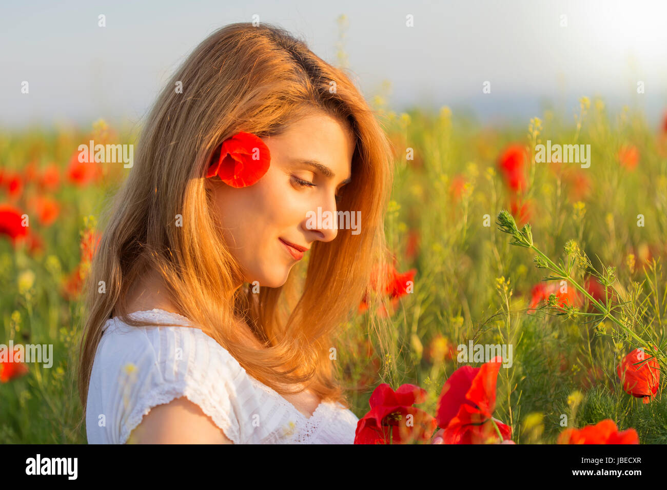 Woman in white dress in a full field of poppies Stock Photo - Alamy