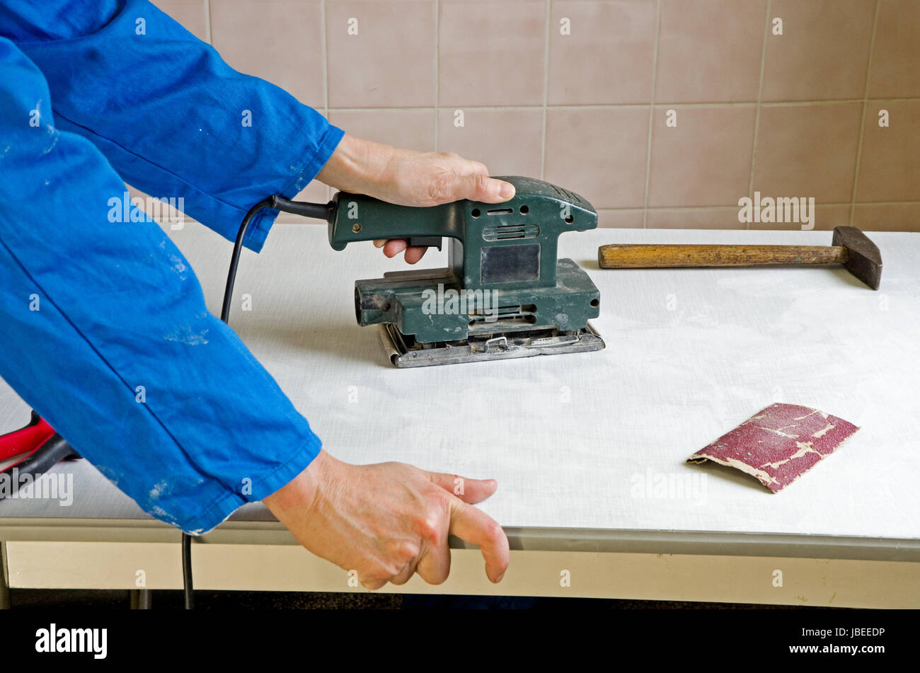 carpenter grinding the surface of a piece of furniture Stock Photo