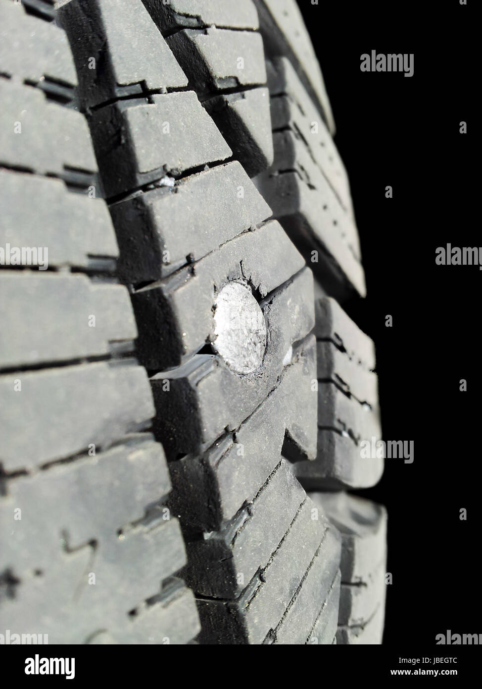 Screw into rubber tire isolated towards black background Stock Photo